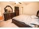 Well-lit bedroom with a carved wood bed frame, dresser, and carpeted flooring at 14430 English Lavender Dr, Wimauma, FL 33598