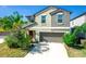 Two-story home featuring a neutral color scheme, two car garage, manicured lawn, and vibrant, mature landscaping at 14430 English Lavender Dr, Wimauma, FL 33598