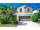 Two-story home with a neutral color scheme, well-kept lawn, two car garage, and tropical landscaping at 14430 English Lavender Dr, Wimauma, FL 33598