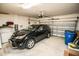 A well-lit two car garage featuring a black SUV, storage, and an automatic door opener at 14430 English Lavender Dr, Wimauma, FL 33598