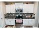Well-equipped kitchen with stainless steel appliances, granite countertops, white cabinets, and tiled backsplash at 14430 English Lavender Dr, Wimauma, FL 33598