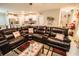 Spacious living room features a large brown leather sectional sofa and an open view of the modern kitchen at 14430 English Lavender Dr, Wimauma, FL 33598