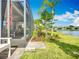 Serene backyard showcasing a screened-in patio, lush greenery, and a peaceful waterfront view on a sunny day at 15434 Santa Pola Dr, Wimauma, FL 33598