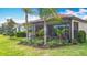 Charming backyard featuring a screened-in patio, mature trees, and well-manicured landscaping under a clear blue sky at 15434 Santa Pola Dr, Wimauma, FL 33598