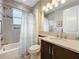 Well-lit bathroom with a shower-tub combo, vanity with a dark wood cabinet, and large mirror at 15434 Santa Pola Dr, Wimauma, FL 33598
