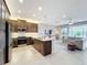 Open-concept kitchen featuring dark wood cabinets, stainless steel appliances, and a large island at 15434 Santa Pola Dr, Wimauma, FL 33598