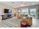 Comfortable living room featuring large windows, a ceiling fan, and an area rug to complement the neutral sofa at 15434 Santa Pola Dr, Wimauma, FL 33598