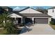 Charming home featuring a two-car garage, covered porch, and tropical landscaping at 197 Rain Berry Ave, Ruskin, FL 33570