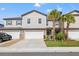 Townhome with two-car garage, driveway, stone accents, landscaping, and palm trees on a sunny day at 21181 Threadfin Way, Land O Lakes, FL 34638