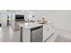 Bright kitchen island featuring white cabinetry and modern stainless steel dishwasher overlooking open living area at 21181 Threadfin Way, Land O Lakes, FL 34638