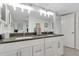 Bright bathroom featuring a double vanity with gray countertop and well-lit mirrors at 223 Island Way # 7H, Clearwater, FL 33767