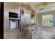Kitchen features a stainless steel refrigerator, tile flooring and window to backyard at 4908 Lynchburg Ct, New Port Richey, FL 34655