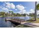 Picturesque lake view featuring a fountain, wooden dock, and attractive lakeside homes under a blue sky at 4908 Lynchburg Ct, New Port Richey, FL 34655