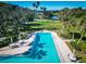 A long swimming pool surrounded by palm trees, tables, and umbrellas sits adjacent to a waterway at 504 S Florida Ave # 225, Tarpon Springs, FL 34689