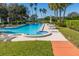 Beautiful community pool area with poolside seating, landscaping and water views in a tropical setting at 504 S Florida Ave # 225, Tarpon Springs, FL 34689