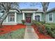 The front entrance of a light-green home, with a decorative door and manicured landscaping at 5501 Stag Thicket Ln, Palm Harbor, FL 34685