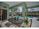 Relaxing screened-in lanai with comfortable seating, lush greenery, and access to the pool area at 5501 Stag Thicket Ln, Palm Harbor, FL 34685