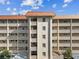 Full frame view of condo building's front, showing many balcony spaces, windows, and central staircase at 620 Edgewater Dr # 204, Dunedin, FL 34698