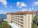View of condo building showing covered parking, units, palm trees, and waterfront views at 620 Edgewater Dr # 204, Dunedin, FL 34698