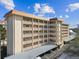 Multi-story condo building with covered parking, exterior corridors, and balcony spaces for each unit at 620 Edgewater Dr # 204, Dunedin, FL 34698