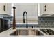 Close up view of modern kitchen sink with marble countertops and unique backsplash at 620 Edgewater Dr # 204, Dunedin, FL 34698