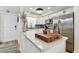 Bright kitchen with white cabinets, stainless steel appliances, and large island with marble countertop at 620 Edgewater Dr # 204, Dunedin, FL 34698