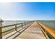 Long wooden pier extending into the water with clear blue sky at 620 Edgewater Dr # 204, Dunedin, FL 34698