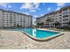 A beautiful, sparkling pool is the focal point of the image, surrounded by lounge chairs and condo buildings at 620 Edgewater Dr # 204, Dunedin, FL 34698