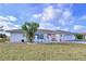 Charming single-story home with white exterior, red front door, manicured lawn, and decorative landscaping at 634 Allegheny Dr, Sun City Center, FL 33573