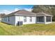 Home's rear exterior showing a lawn, stucco siding, and a screened in patio at 7541 Mariners Harbour Dr, Wesley Chapel, FL 33545