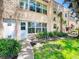 Well-maintained stucco condominium exterior with multiple windows, landscaped yard, and sidewalk at 110 Aspen Cir, Seminole, FL 33777