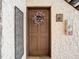 Charming brown front door with a floral wreath, textured walls, and decorative wall art at 110 Aspen Cir, Seminole, FL 33777