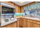 Detailed view of kitchen featuring vintage cooktop, wood cabinets, tiled backsplash, and window view at 1421 Monte Carlo Dr, Clearwater, FL 33764