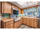 Charming kitchen with wood cabinets, a vintage cooktop, tiled backsplash, and a window with patterned valance at 1421 Monte Carlo Dr, Clearwater, FL 33764