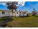 View of the backyard showcasing a green lawn, a palm tree, and partial views of the home's exterior at 1517 Danbury Dr, Sun City Center, FL 33573