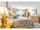 This is a primary bedroom with a blue bedspread, soft lighting, and wood laminate flooring at 1750 Belleair Forest Dr # A7, Belleair, FL 33756