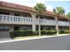 Two-story condo featuring a red tile roof, second story balconies, and manicured landscaping at 1750 Belleair Forest Dr # A7, Belleair, FL 33756