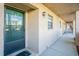 Exterior view of condo building with stucco walls, black framed glass door, and carpeted walkway at 1750 Belleair Forest Dr # A7, Belleair, FL 33756
