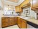 Well-lit kitchen featuring wood cabinets, tile backsplash, and modern appliances at 1750 Belleair Forest Dr # A7, Belleair, FL 33756