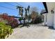 A concrete paved exterior showcasing lush greenery with palms against a white picket fence at 2100 Mcmullen Rd, Largo, FL 33771