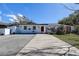 Exterior view of a single-story home with a red door, white trim and large driveway at 2100 Mcmullen Rd, Largo, FL 33771
