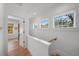 Upstairs hallway with multiple windows and hardwood floors leading to bedroom and bath at 2412 W Sunset Dr, Tampa, FL 33629