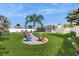 Lush backyard oasis with vibrant adirondack chairs, mature palms, and cozy patio, a perfect retreat at 2504 Bayshore Dr, Belleair Beach, FL 33786