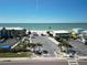 View of the beach and parking area with palm trees and nearby buildings at 2504 Bayshore Dr, Belleair Beach, FL 33786