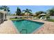 Sparkling pool with brick trim surrounded by lush landscaping offers a serene backyard retreat at 2504 Bayshore Dr, Belleair Beach, FL 33786