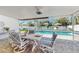 Inviting screened porch features dining set, fan, and stunning pool view, perfect for outdoor relaxation at 2504 Bayshore Dr, Belleair Beach, FL 33786