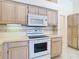 Close-up of a kitchen featuring an oven, microwave, and light wood cabinets for a functional cooking area at 2725 Onizuka Ct, Palm Harbor, FL 34683