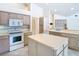 Well-lit kitchen featuring an island, white appliances, and cabinets with plenty of storage at 2725 Onizuka Ct, Palm Harbor, FL 34683