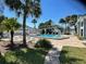 Community pool with lounge chairs, palm trees, and manicured landscaping at 2757 Countryside Blvd # 103, Clearwater, FL 33761