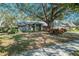 Inviting single-story brick home with well-manicured lawn, a mature tree, and an attached two-car garage at 3013 Ridgevale Cir, Valrico, FL 33596
